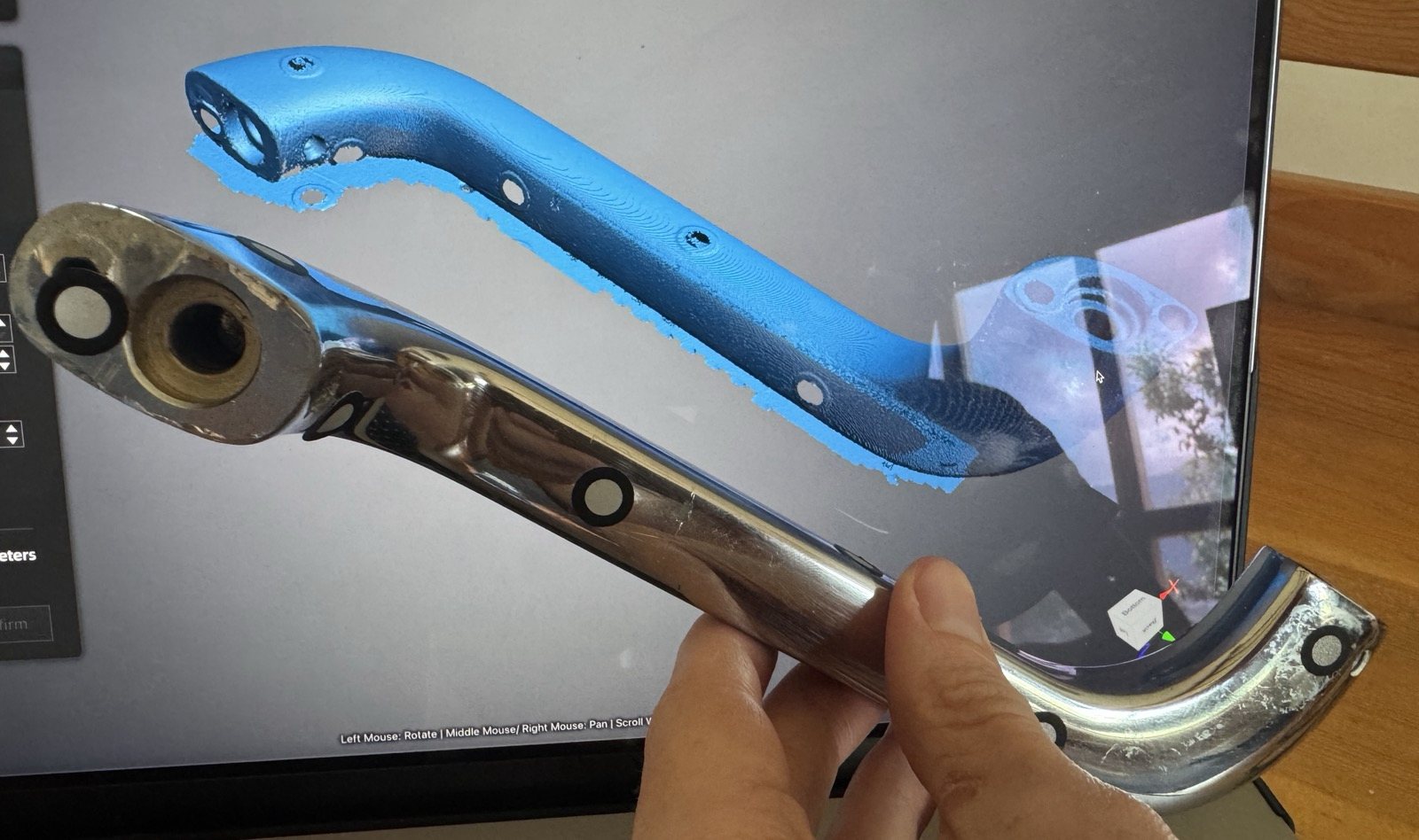 The chrome handle held in front of the screen, beside its 3D scan